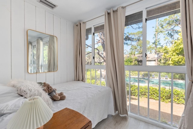 bedroom with access to outside, wood walls, and light hardwood / wood-style flooring