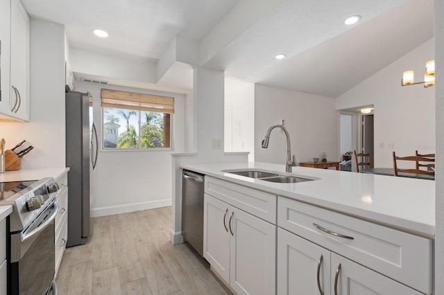 kitchen with stainless steel appliances, vaulted ceiling, sink, light hardwood / wood-style flooring, and white cabinets