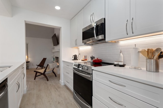 kitchen featuring backsplash, white cabinets, stainless steel appliances, and light hardwood / wood-style floors