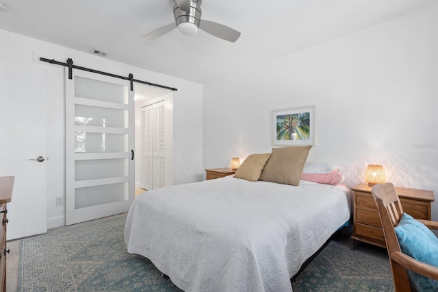 bedroom featuring ceiling fan, a barn door, and a closet