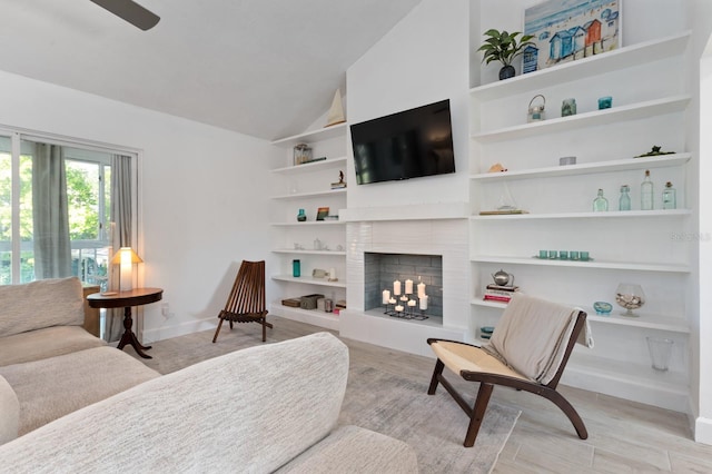 living room featuring built in shelves, light wood-type flooring, ceiling fan, and lofted ceiling