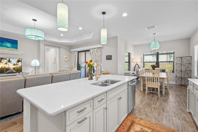 kitchen featuring sink, stainless steel dishwasher, a center island with sink, and light wood-type flooring