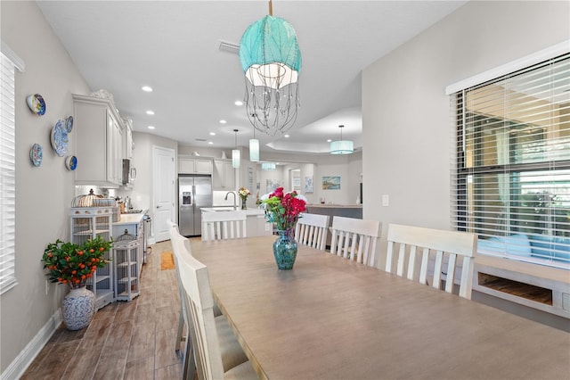 dining space with a notable chandelier, sink, and light hardwood / wood-style flooring