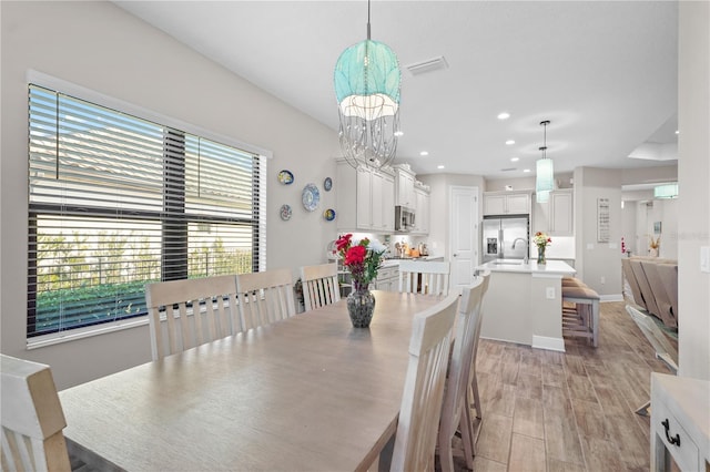 dining room featuring light wood-type flooring, sink, and a chandelier