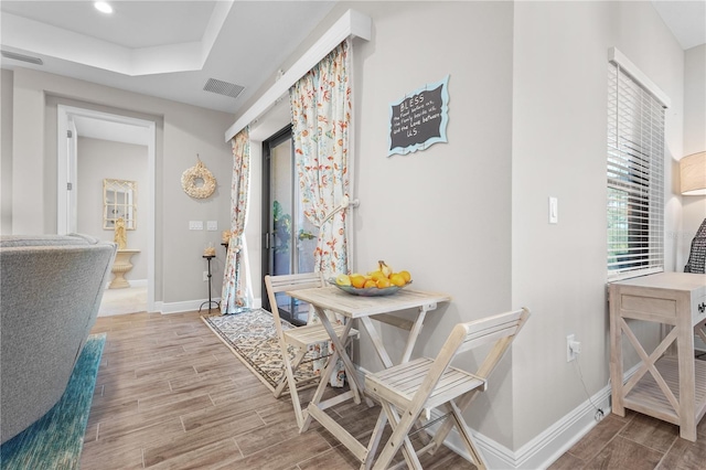 dining space featuring a raised ceiling and light hardwood / wood-style flooring