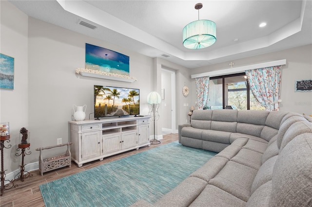 living room featuring hardwood / wood-style flooring and a raised ceiling