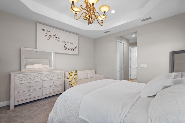 bedroom with carpet flooring, a raised ceiling, a closet, and a notable chandelier