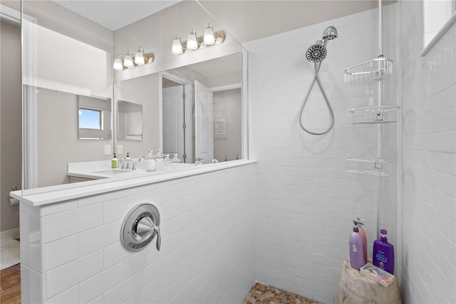 bathroom with hardwood / wood-style flooring, vanity, and tiled shower