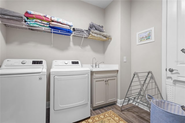 laundry room with washer and clothes dryer, dark hardwood / wood-style flooring, cabinets, and sink