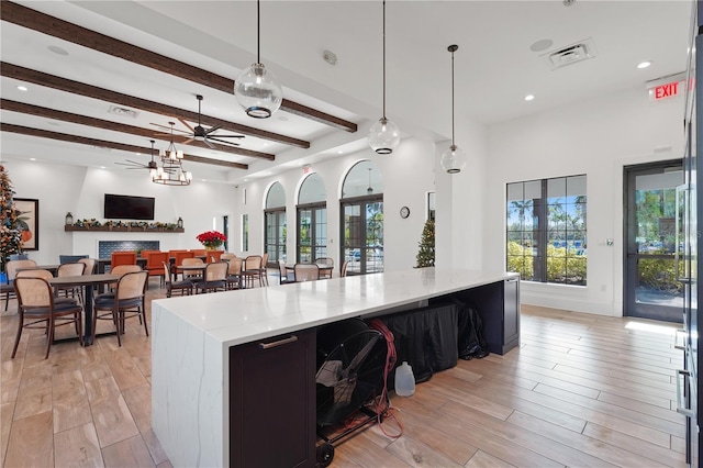 kitchen featuring a center island, light hardwood / wood-style flooring, ceiling fan, beamed ceiling, and decorative light fixtures