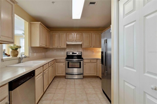 kitchen with light brown cabinets, sink, stainless steel appliances, and tasteful backsplash