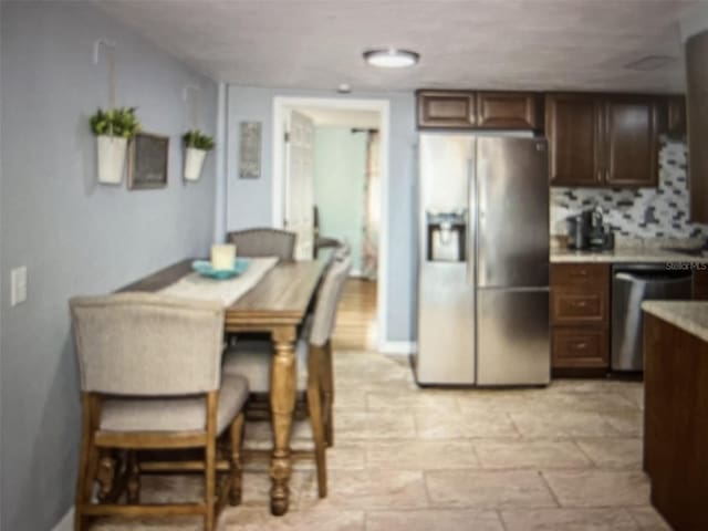 kitchen with appliances with stainless steel finishes, dark brown cabinetry, and tasteful backsplash