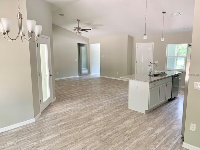 kitchen with light stone countertops, dishwasher, a center island with sink, ceiling fan with notable chandelier, and light wood-type flooring