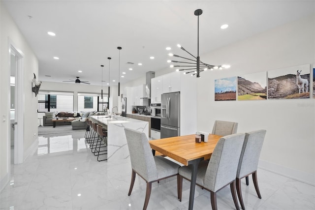 dining space featuring ceiling fan with notable chandelier and sink