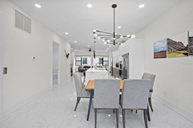 dining space with ceiling fan with notable chandelier and sink