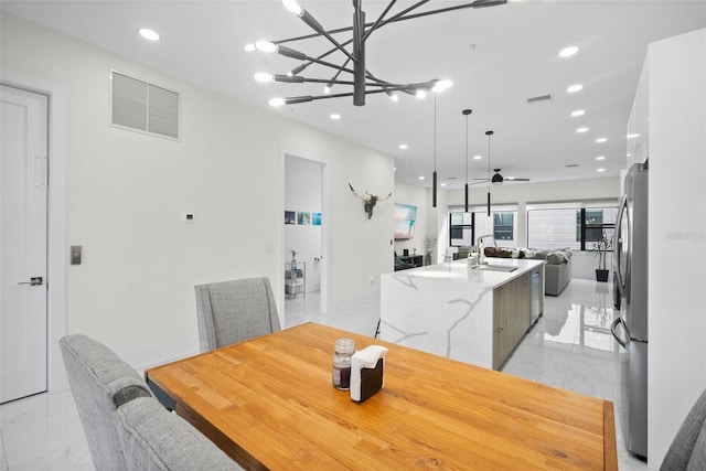 dining room with ceiling fan with notable chandelier and sink