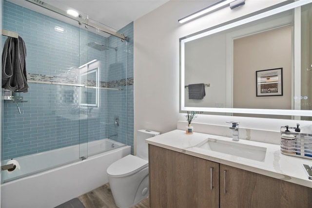 full bathroom with combined bath / shower with glass door, wood-type flooring, vanity, and toilet