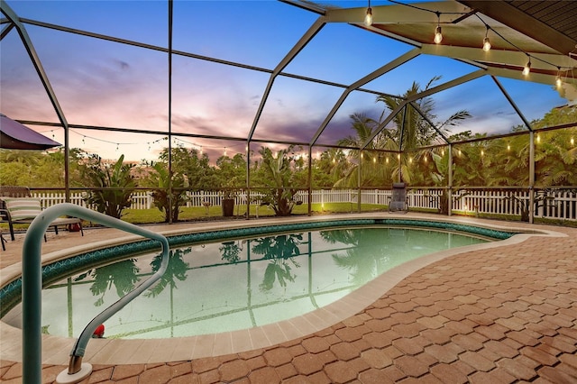 pool at dusk featuring a lanai