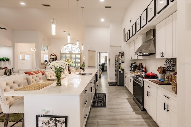 kitchen featuring pendant lighting, exhaust hood, white cabinets, sink, and appliances with stainless steel finishes