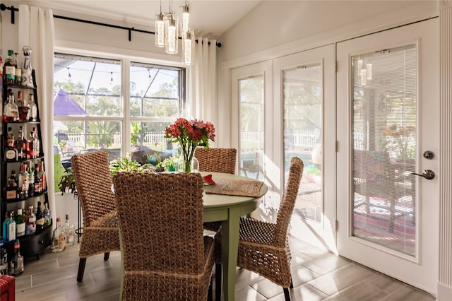 dining room with a chandelier, vaulted ceiling, and light wood-type flooring