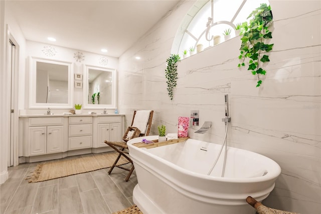 bathroom featuring a tub to relax in, vanity, and tile walls