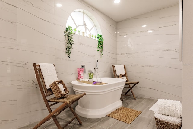 bathroom with a washtub and tile walls