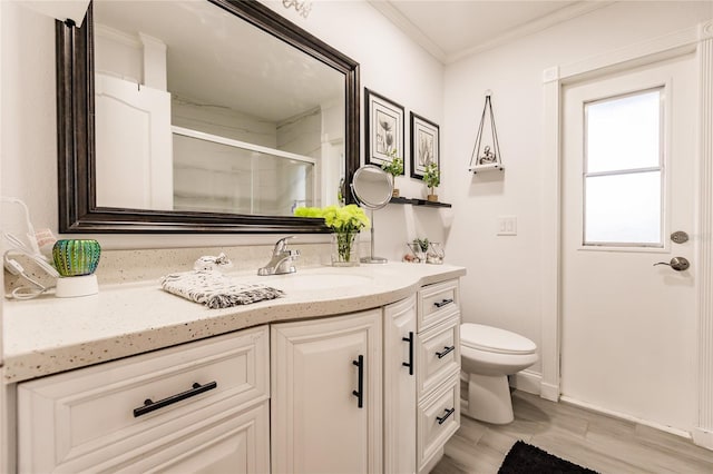 bathroom with an enclosed shower, vanity, crown molding, hardwood / wood-style flooring, and toilet