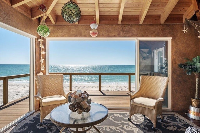 sunroom featuring a beach view, a water view, beamed ceiling, and wood ceiling