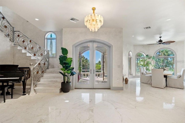 foyer entrance with french doors and ceiling fan with notable chandelier