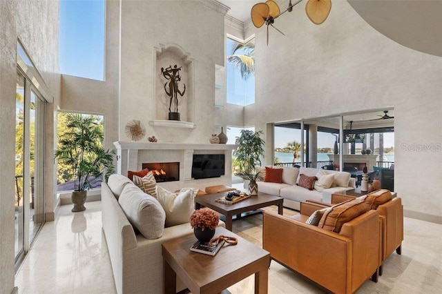 living room featuring a towering ceiling, a water view, and ceiling fan