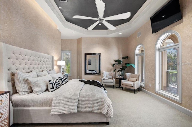 bedroom with a raised ceiling, ceiling fan, and carpet flooring