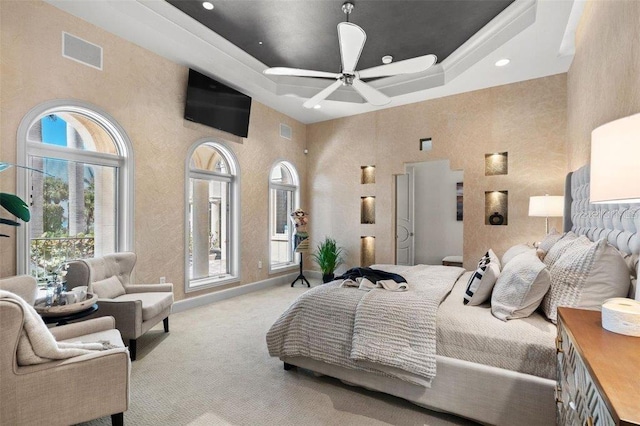 bedroom featuring a towering ceiling, a raised ceiling, and ceiling fan