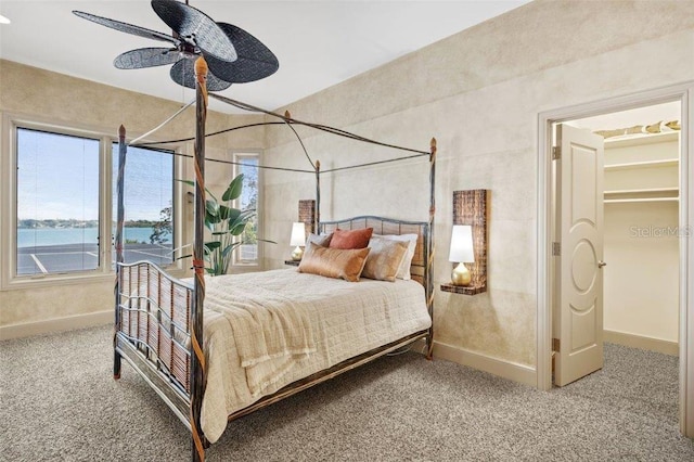 carpeted bedroom with a water view and ceiling fan