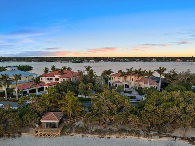 aerial view at dusk featuring a water view