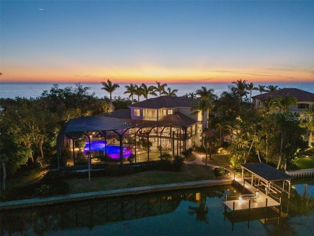 back house at dusk featuring a yard and a water view