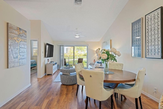 dining room featuring wood-type flooring, a textured ceiling, vaulted ceiling, and ceiling fan