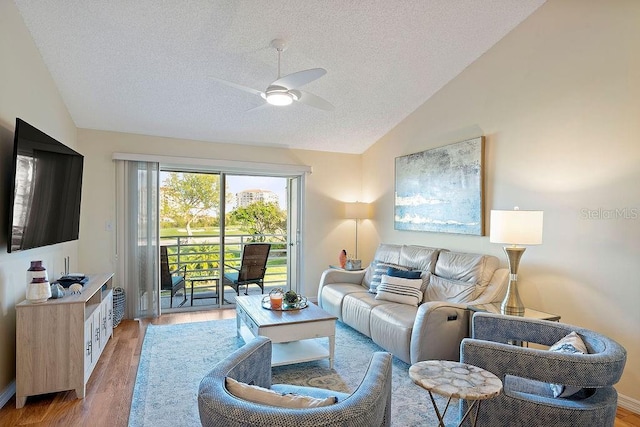 living room with hardwood / wood-style flooring, ceiling fan, vaulted ceiling, and a textured ceiling