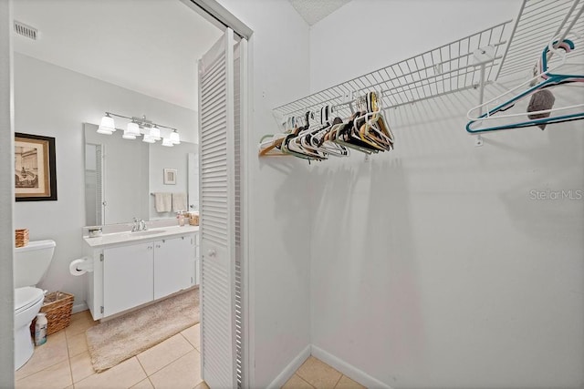 spacious closet featuring visible vents, a sink, and light tile patterned floors