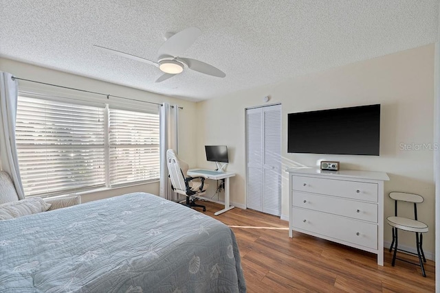 bedroom with a textured ceiling, ceiling fan, wood finished floors, baseboards, and a closet