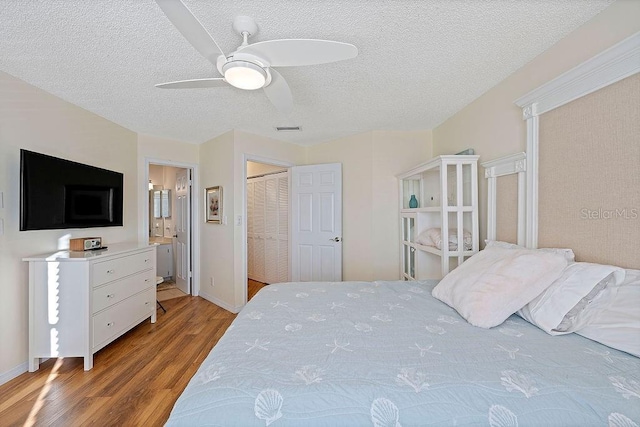 bedroom featuring light hardwood / wood-style floors, a textured ceiling, ceiling fan, and ensuite bath