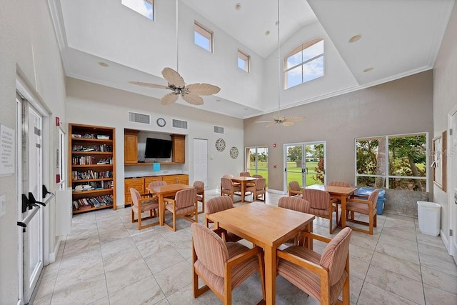 dining space with ceiling fan, a towering ceiling, plenty of natural light, and ornamental molding