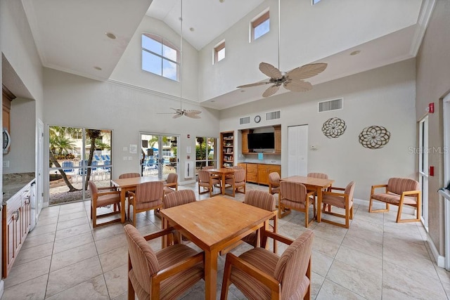 tiled dining area with ceiling fan and a high ceiling