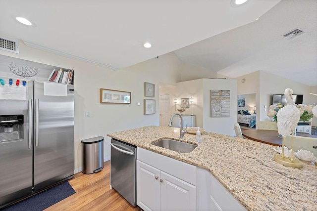 kitchen featuring white cabinetry, lofted ceiling, sink, stainless steel appliances, and light stone countertops