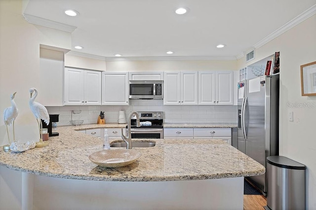 kitchen featuring light stone countertops, appliances with stainless steel finishes, white cabinets, and ornamental molding