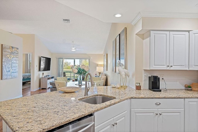 kitchen featuring sink, white cabinetry, light stone counters, ceiling fan, and backsplash