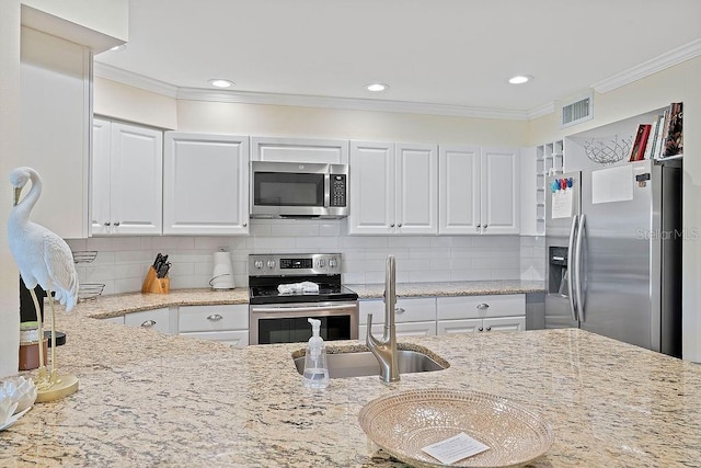 kitchen with visible vents, white cabinets, appliances with stainless steel finishes, light stone counters, and crown molding