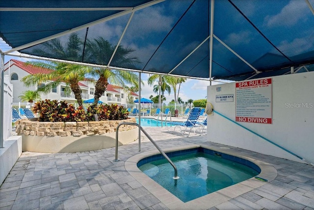 community pool with a community hot tub, a patio area, and fence