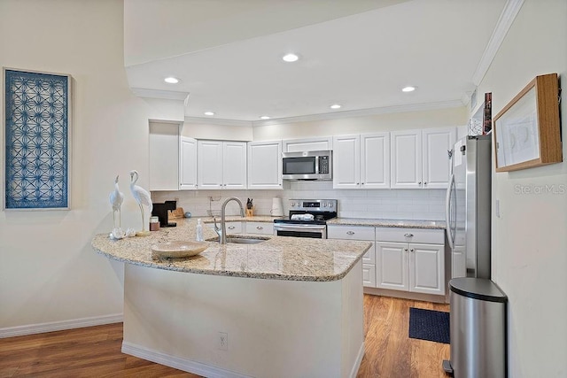 kitchen with appliances with stainless steel finishes, a sink, light stone countertops, and white cabinets