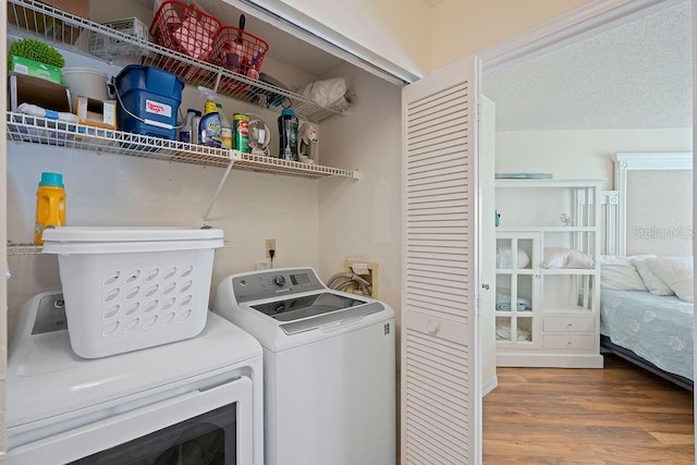 washroom featuring laundry area, wood finished floors, and washing machine and clothes dryer