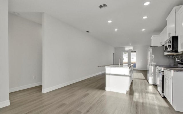 kitchen with light wood-type flooring, stainless steel appliances, a kitchen island with sink, sink, and white cabinets